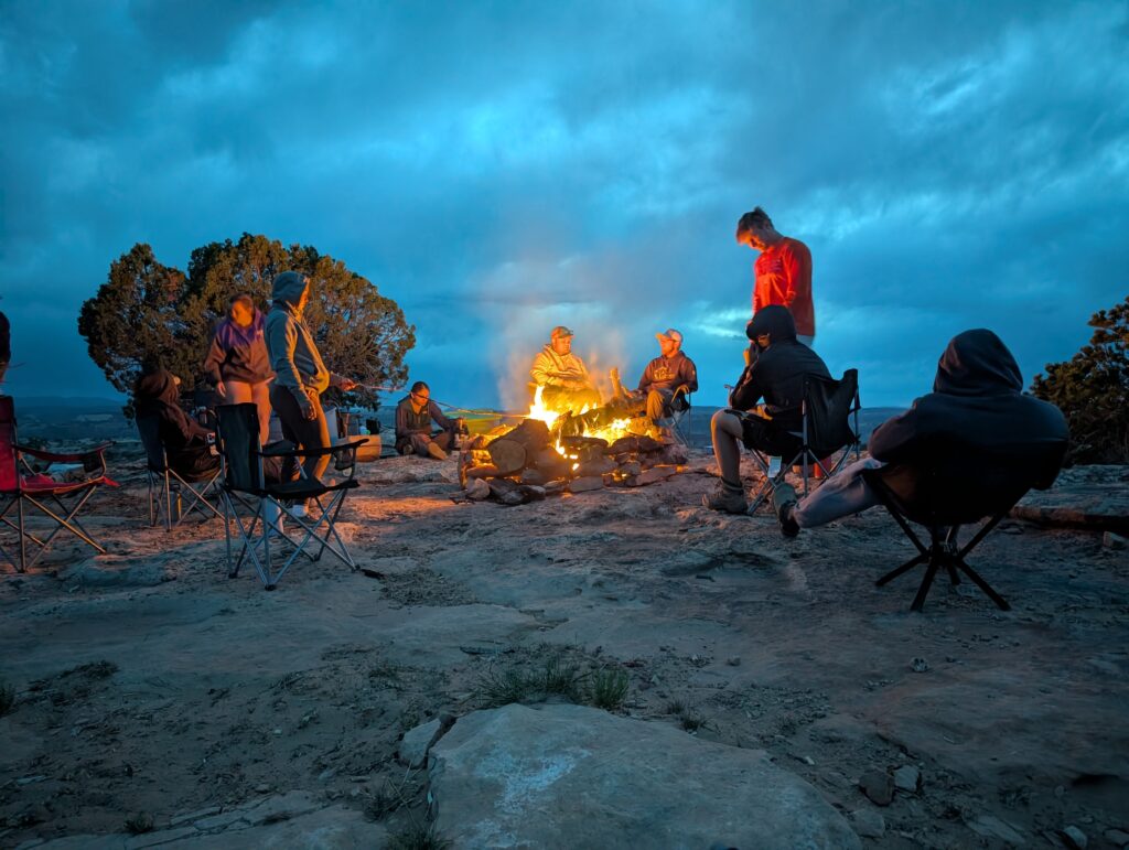 School of Science & Agriculture Students gather around a campfire on a rocky ridge at dusk.